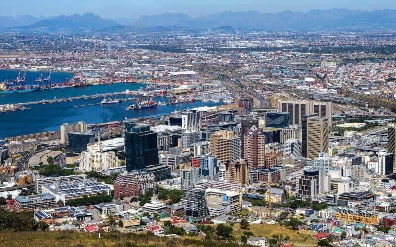 Toàn cảnh trung tâm thành phố Cape Town với đường chân trời và bến cảng nhộn nhịp, có núi non ở phía xa.