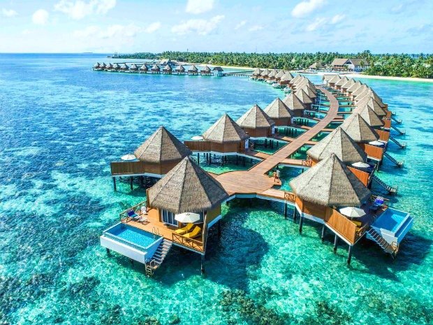 Dãy bungalow trên nước sang trọng ở khu nghỉ dưỡng Maldives, nổi bật trên nền nước biển trong xanh và bầu trời trong.