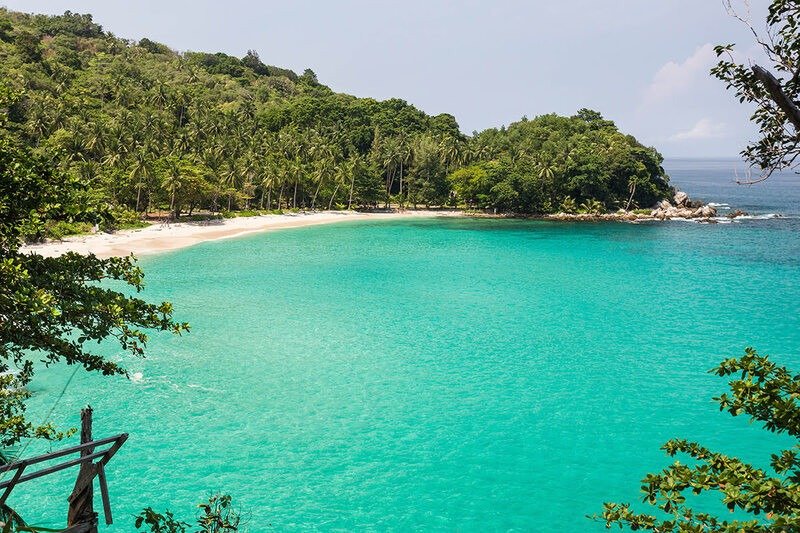 Vịnh biển trong xanh với bãi cát trắng và rừng cây nhiệt đới, tạo nên khung cảnh thiên nhiên hoang sơ, yên bình.