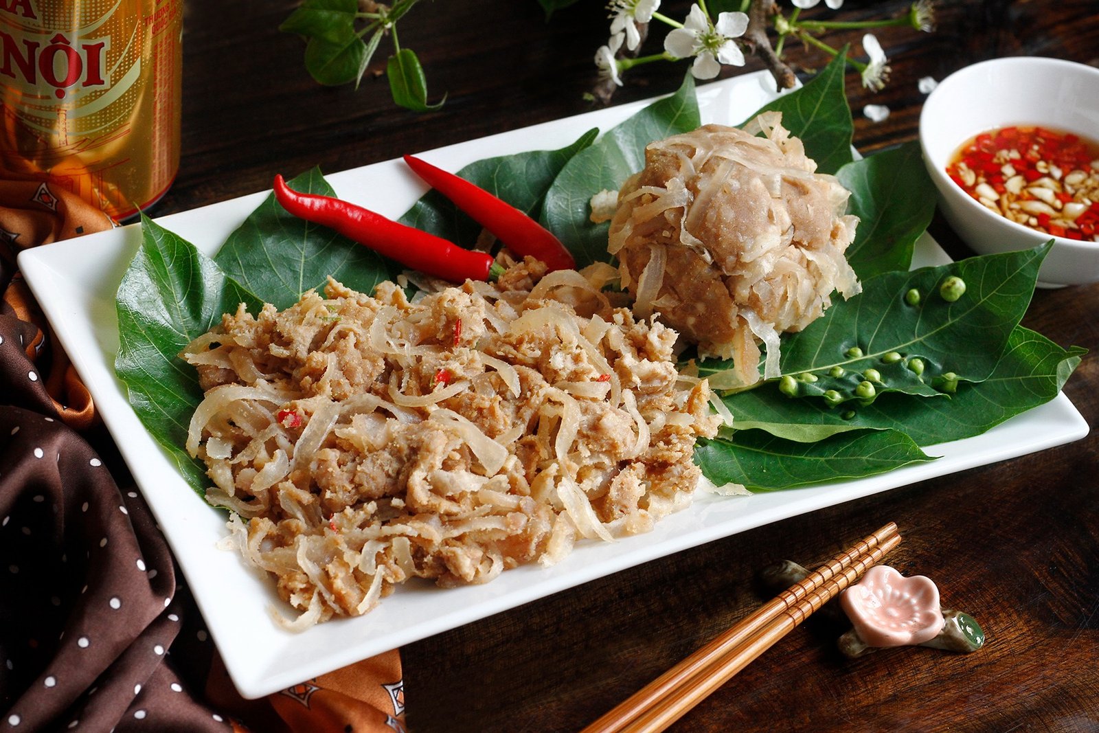Món nem chua Bắc làm từ thịt lợn và bì, được trang trí với lá và ớt đỏ, đặt trên đĩa trắng.