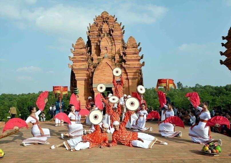 Các vũ công mặc trang phục truyền thống biểu diễn trước tháp gạch đỏ ở Việt Nam, tạo hình đầy màu sắc.