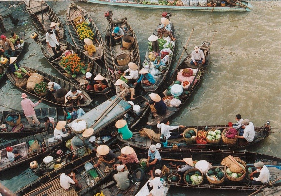 Chợ nổi sôi động với những chiếc thuyền đầy trái cây tươi ngon và người mua bán nhộn nhịp trên mặt nước.