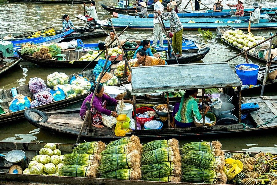 Chợ nổi tấp nập tại Việt Nam với nhiều thuyền bán rau củ và nông sản tươi sống trên mặt nước.