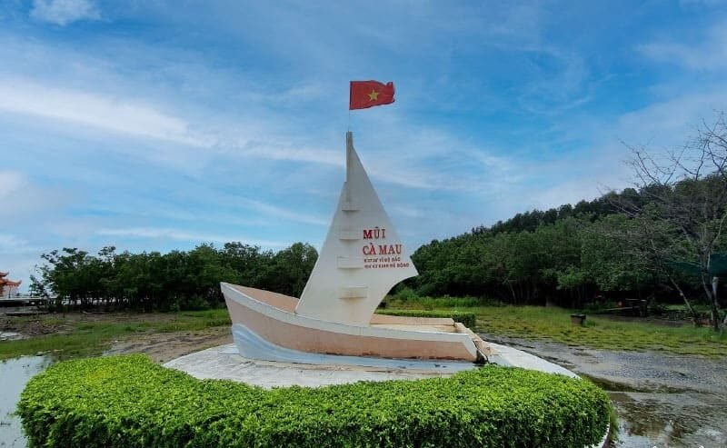 Tượng hình con thuyền tại Mũi Cà Mau, biểu tượng cực Nam của Việt Nam, với cờ đỏ sao vàng tung bay.