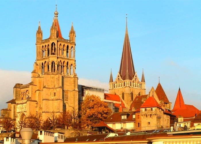 Nhà thờ Lausanne, Thụy Sĩ nổi bật với kiến trúc Gothic uy nghi, ánh nắng vàng chiếu rọi trong một buổi chiều trời trong xanh.